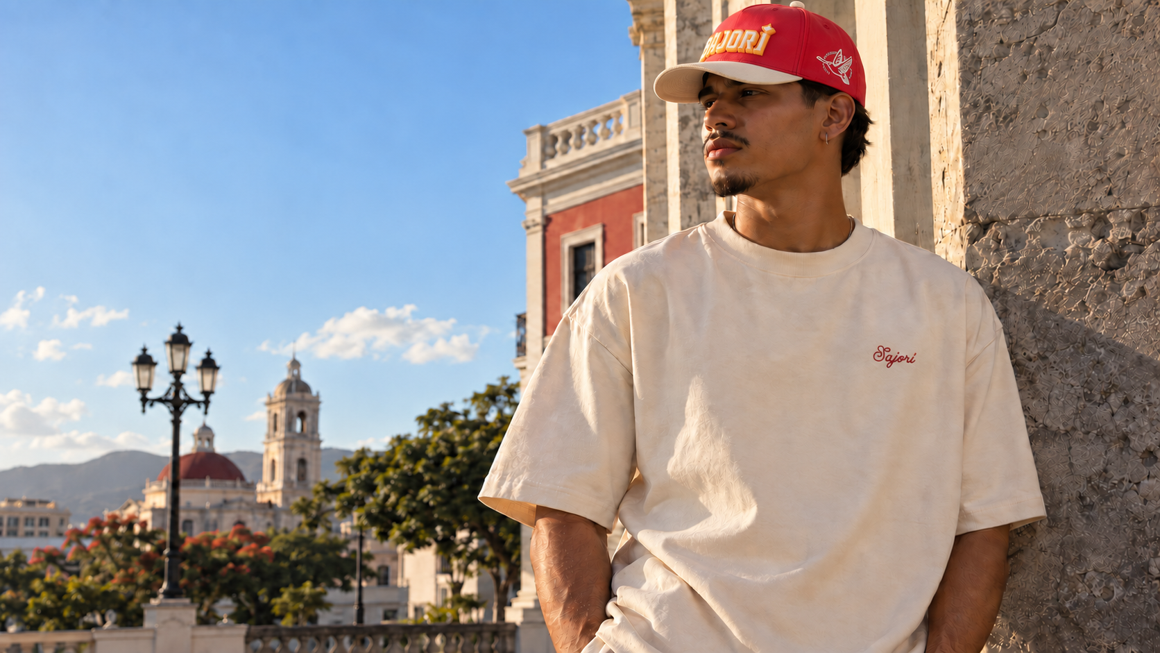 Modelo vistiendo camisa crema bordada y gorra roja Sajorí con visera crema en Ponce